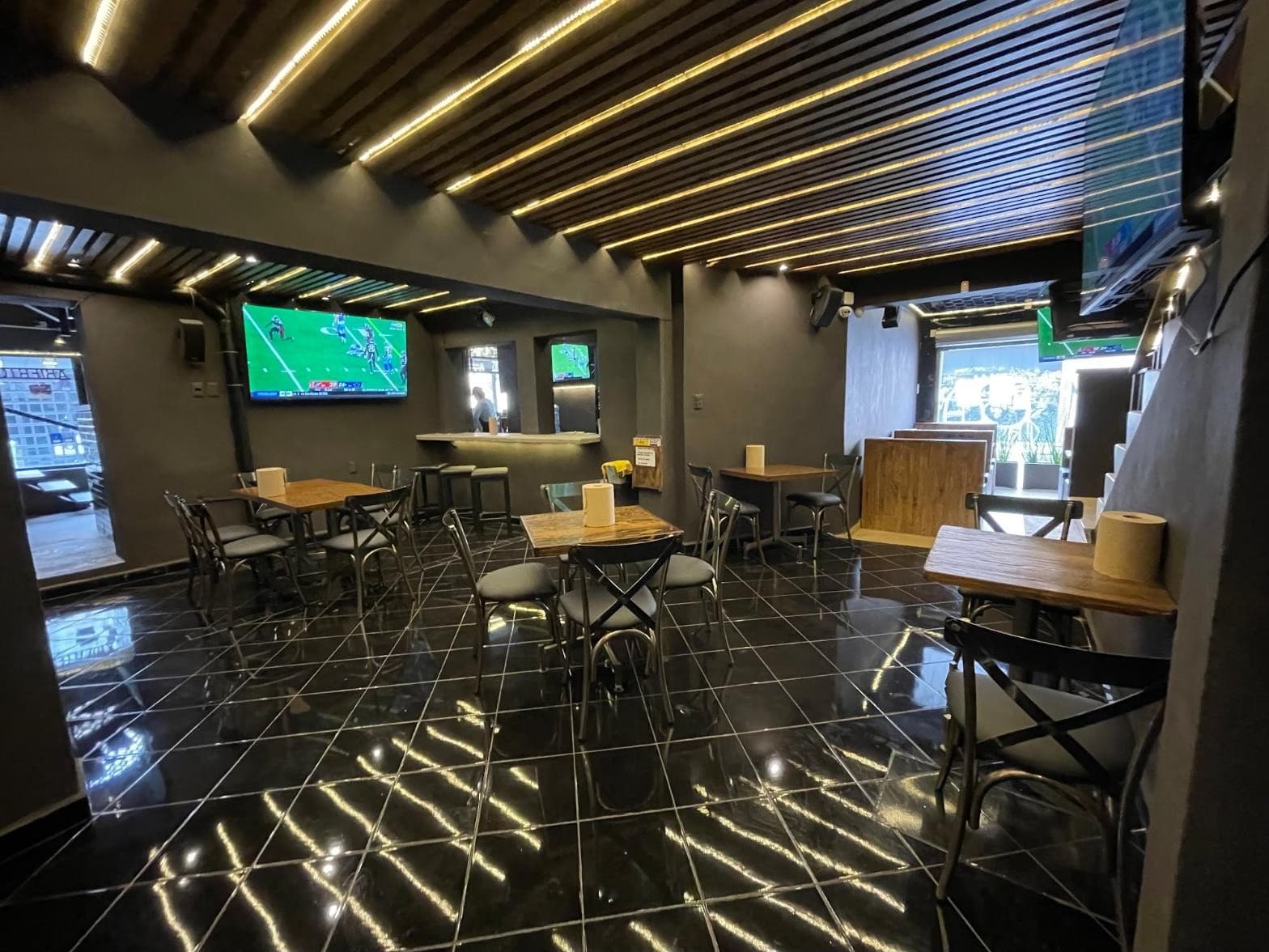 Salón con techo de listones de madera iluminado y pantallas