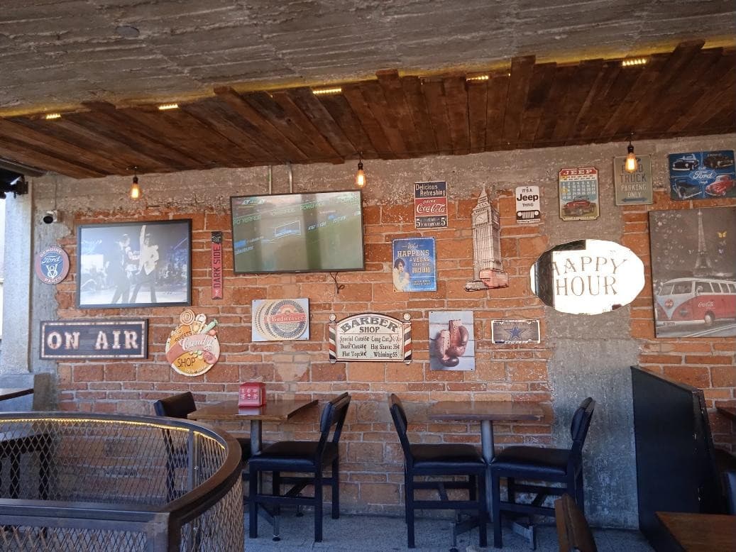 Pared de ladrillo con letreros vintage y espejo Happy Hour